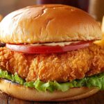 Crispy Fried Chicken Burger With Fresh Toppings And Golden Fries On A Wooden Table